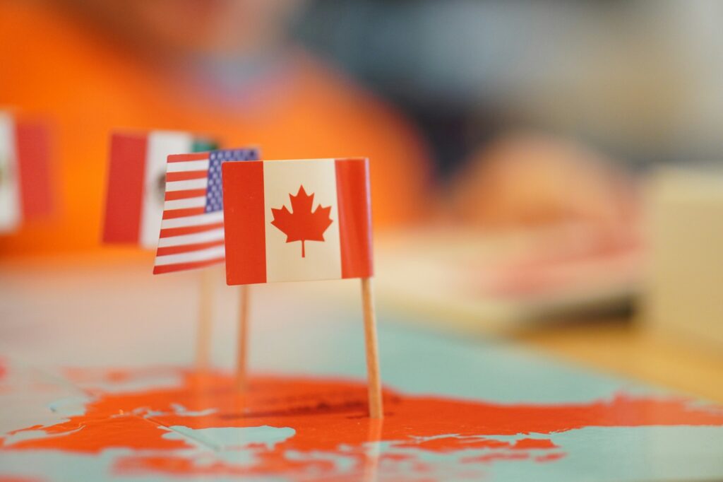 Selective focus shot of North American country flag pins pinned on a flat map